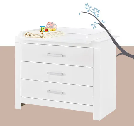 Weiße Wickelkommode mit weißem Wickelaufsatz mit Decke und Spielzeug darauf, gelber Hintergrund und Ast mit Blättern