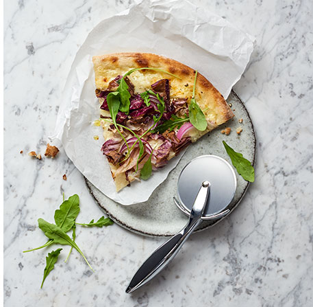 Teller, Pizza, Pizzaschneider und Papier - im Hintergrund weißer Marmor