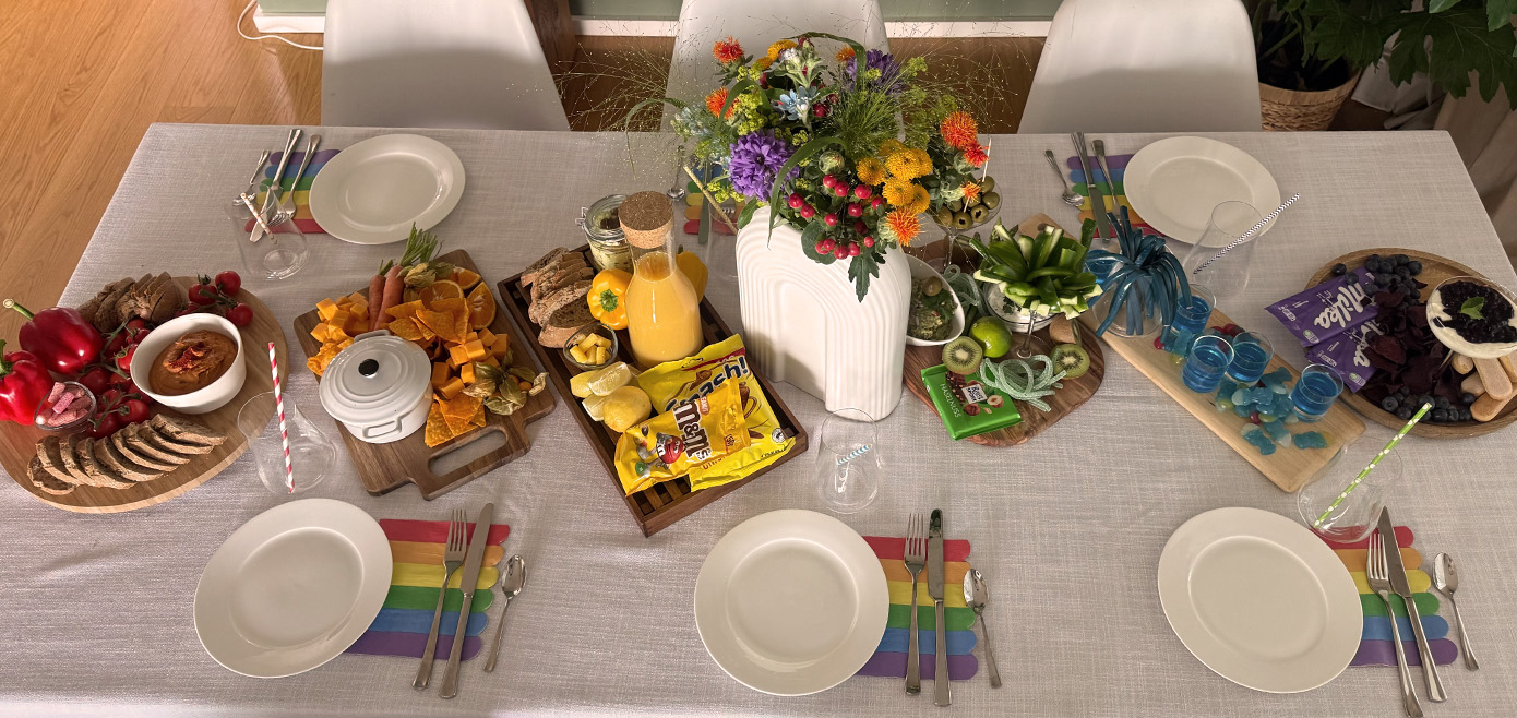 Bunte Snacks nach Regenbogenfarben sortiert, buntes Tablesetting