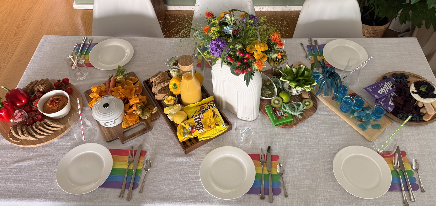 Bunte Snacks nach Regenbogenfarben sortiert, buntes Tablesetting