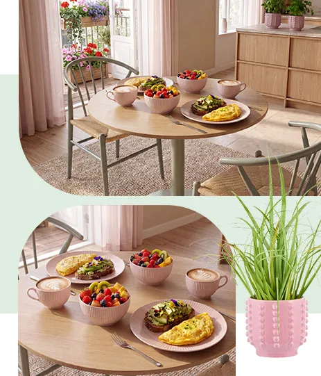 Kleiner runder Esstisch aus hellem Holz mit olivefarbenem Fuß, passend dazu Essstühle ebenfalls aus hellem Holz und olivefarbenem Gestell, rosa Essteller, Schalen und Kaffeetassen, rosaner Blumentopf
