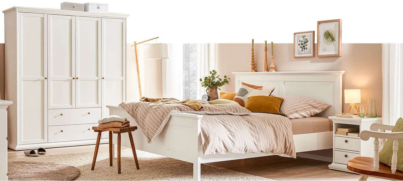 Schlafzimmer mit weißen Möbeln der Serie: Kleiderschrank mit 4 Türen und 2 Schubladen, Nachttisch. Dazu ein weißes Doppelbett.