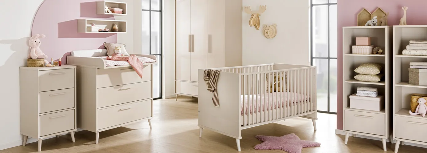 Babyzimmer mit beigen Babymöbeln im Skandistil, bestehend aus Kommode, Wickelkommode mit Wickelaufsatz und rosa Wickelauflage, 2 Wandboards, Schrank, Kinderbett, 2 Regale, Deko und Spielsachen