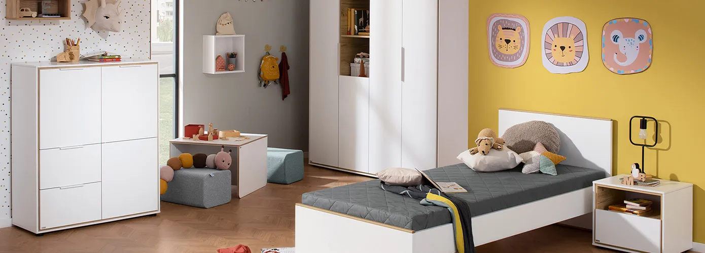 Kinderzimmer mit weißen Kindermöbeln mit Holzakzenten, bestehend aus Highboard, Wandboard, Tisch, Schrank, Bett und Nachtkommode