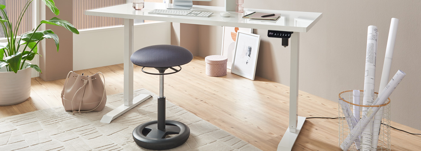 Weißer Schreibtisch und schwarzer Steh-Hocker, darunter ein cremefarbener Teppich