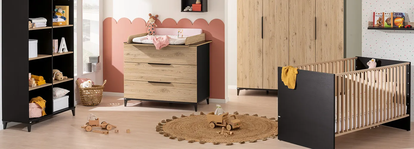Babyzimmer mit Babymöbeln in Schwarz und Eichenoptik, bestehend aus Regal, Wickelkommode mit Wickelauflage, Schrank und Babybett. Deko und Spielzeug.