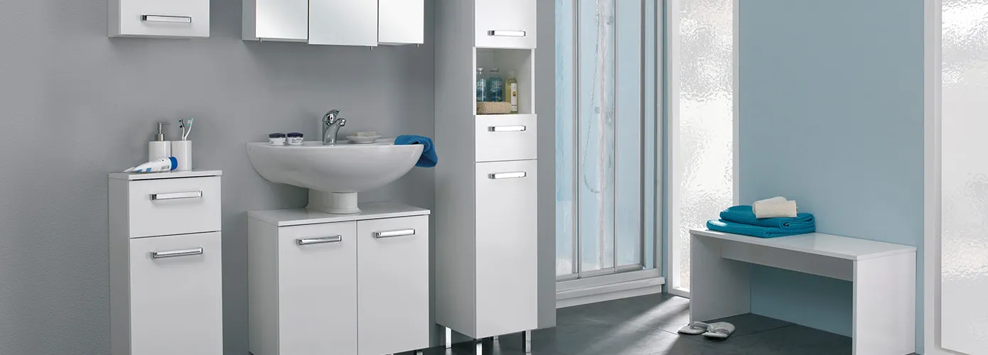 Badezimmer mit weißen Badmöbeln, bestehend aus Hängeschrank und Unterschrank, Spiegelschrank, Waschbeckenunterschrank, Hochschrank vor grauer Wand, Dusche, weiße Bank vor hellblauer Wand
