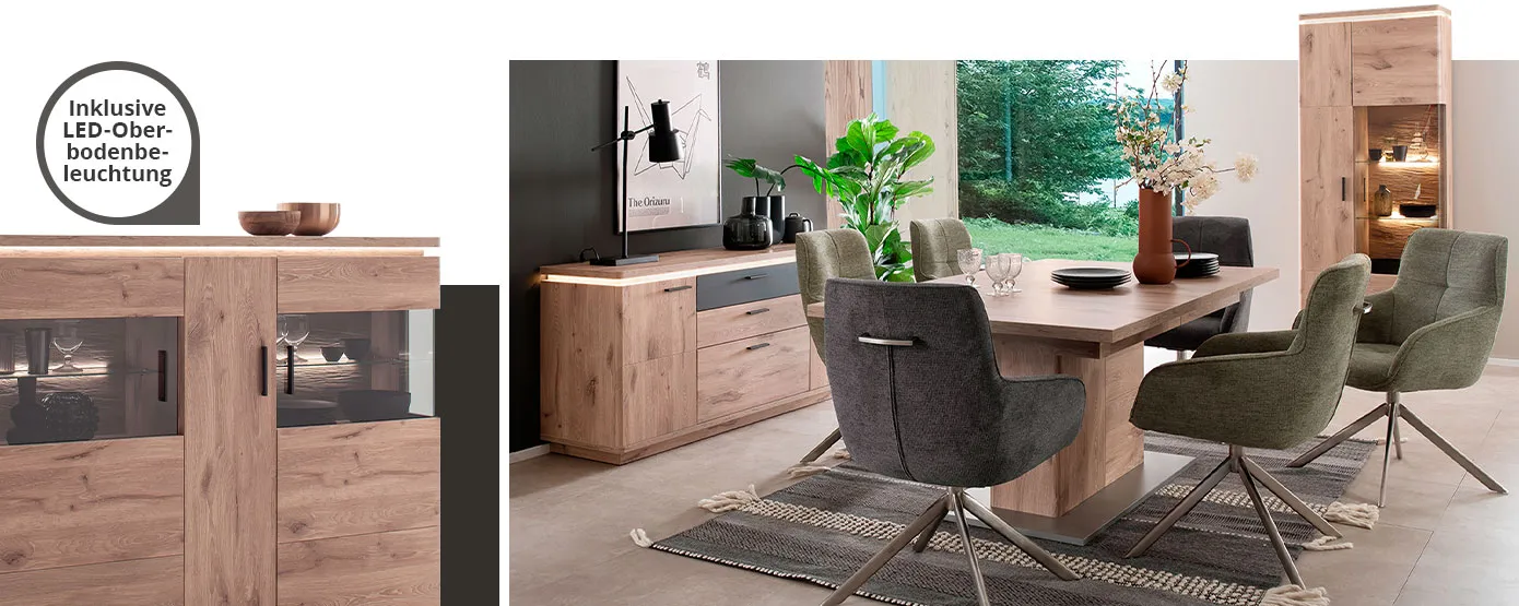Detail eines beleuchteten Highboards in Holzoptik mit Hinweis: Inklusive LED-Oberbodenbeleuchtung, Esszimmer mit Möbeln in Holzoptik, bestehend aus Sideboard mit anthrazitfarbigem Akzent, Vitrine, beide mit LED-Oberbodenbeleuchtung, sowie Esstisch und grünen und grauen Polsterstühlen, Deko