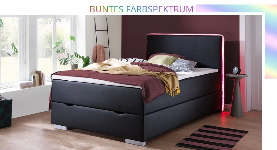 Buntes Farbspektrum. Schlafzimmer mit schwarzem Boxspringbett mit umlaufender Beleuchtung in Rot am Kopfteil