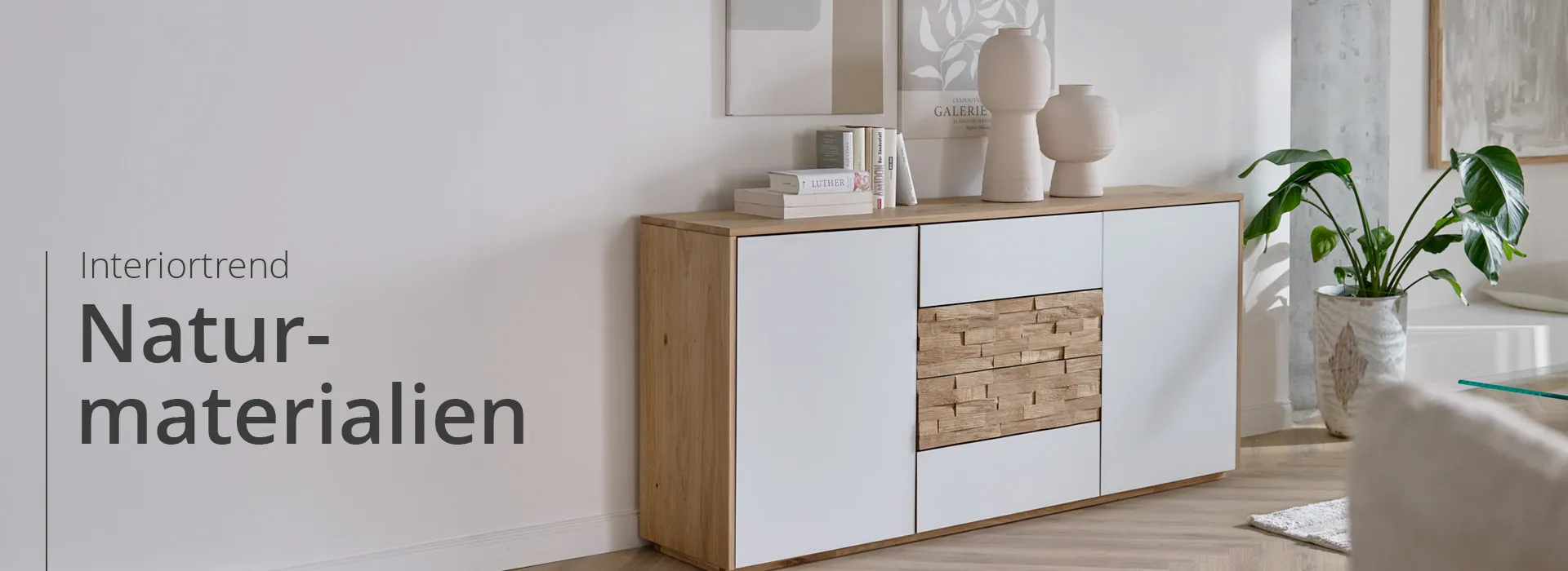 Holzkommode mit weißer Front und Holz-Schubladen, beige Steinvasen, große Pflanze