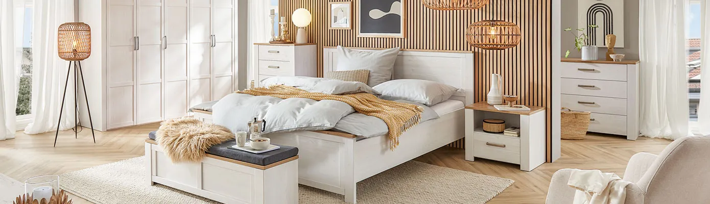 Schlafzimmer mit weißen Landhausmöbeln mit Holzakzenten, bestehend aus Schrank, Bett, Kommode, Nachtkommode und Bettbank