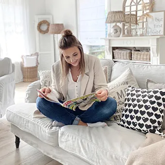 Frau auf Landhaus-Sofa in einem Wohnzimmer im Landhausstil