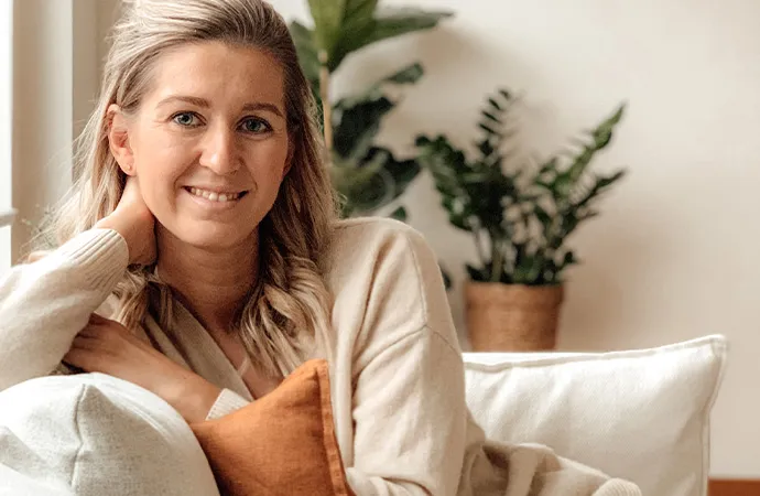 Frau auf weißem Sofa mit orangem Kissen