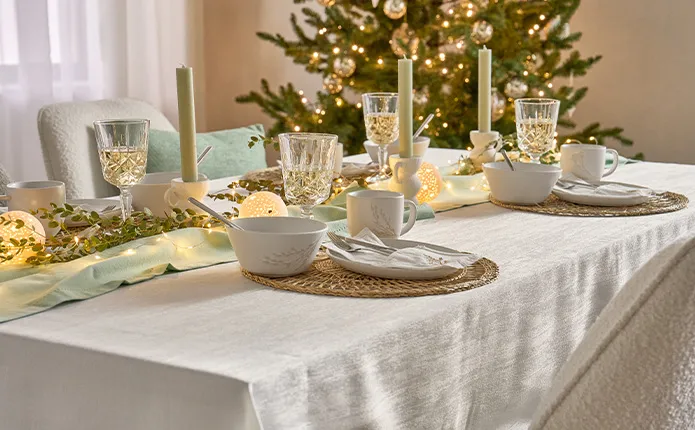 Runde Platzsets in Flechtoptik, weißes Geschirr, mintgrüner Läufer, LED-Lichterkette, grüne Sträucher und grüne Stabkerzen