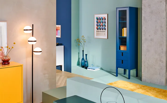 Mintgrüne Wand und Boden, blauer schmaler Vitrinenschrank und blaue Vasen