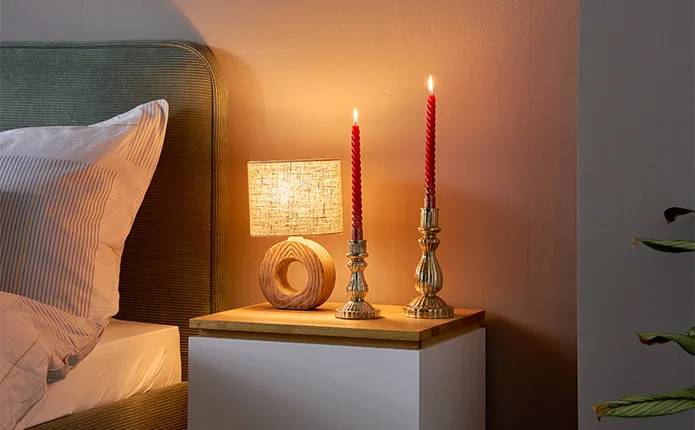 Detailansicht Nachttisch mit Holz-Tischlampe und roten Stabkerzen