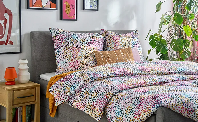 Detailansicht gepunktete, bunte Bettwäsche, kleiner Holz-Nachttisch