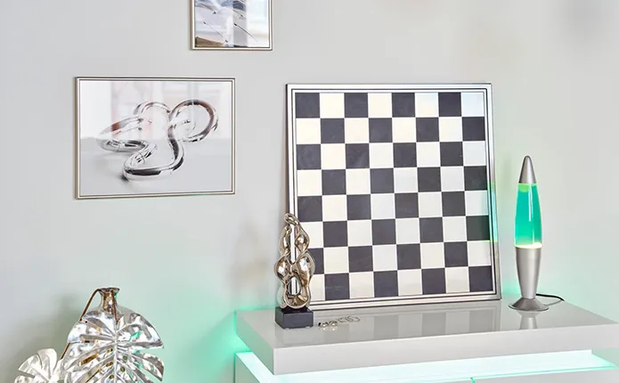 Detailansicht Deko auf Kommode, Schachbrett-Bild, Lavalampe und Chrome-Dekoobjekt