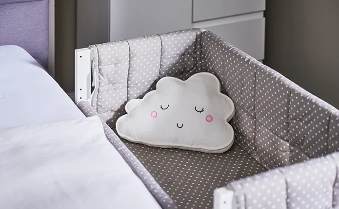 Detailansicht ins Babybett mit Wolkenkissen
