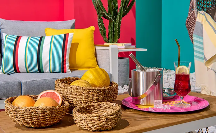 Gestreifte Kissen, buntes Serviertablett, Sektkühler und Flechtkörben für Früchte