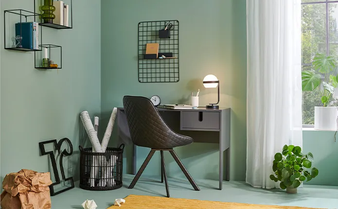 Schreibtischecke mit schwarzem Stuhl, Tisch und Wandregalen, mintfarbene Wand