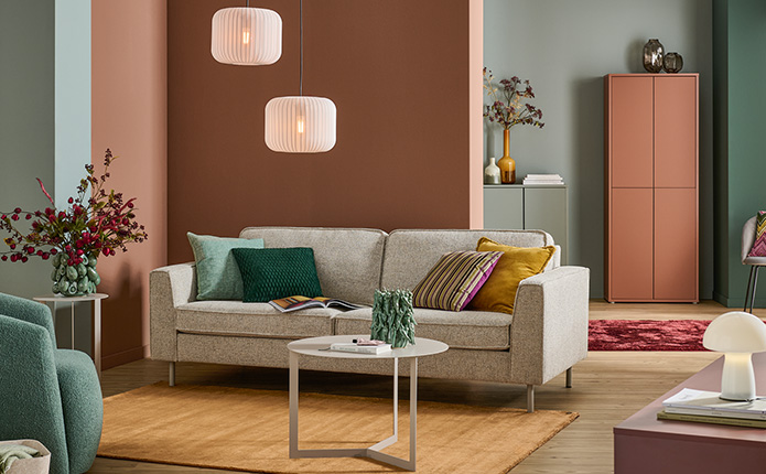 Beige Relaxliegen mit Terracotta- und orangefarbenen Kissen, Pendelleuchten in Flechtoptik, Pflanzen