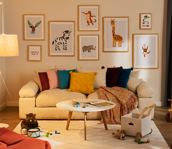 Sofa mit bunten Kissen, vielen bunten Tiermotiven an der Wand, Spielwagen