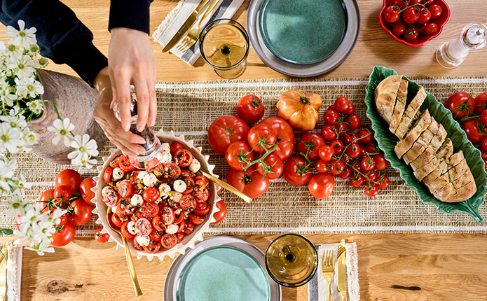 Ansicht von oben mit Tomatensalat, Blattschale, Tomaten und Geschirr auf Holztisch