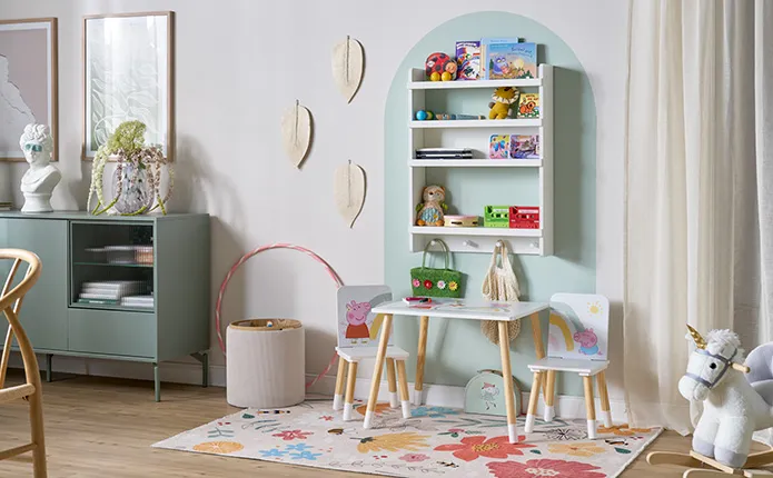 Grüngraue Kommode, Spielecke mit kleinem Tisch und Stuhlset mit Pepper Pig, kleiner Teppich mit Blumen, Wandregal mit Spielzeug, farblicher Rundbogen an Wand zur Abgrenzung