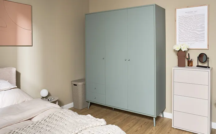 Kleiderschrank in Graugrün, daneben beige Kommode mit vier Schubladen