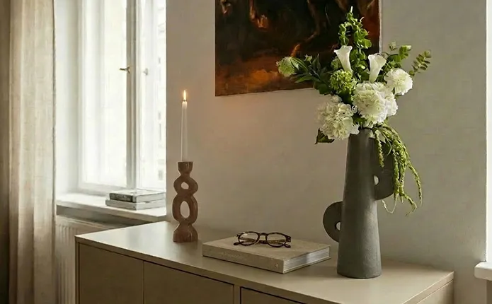 Lowboard mit grauer Vase in Steinoptik, Kerzenständer aus Holz