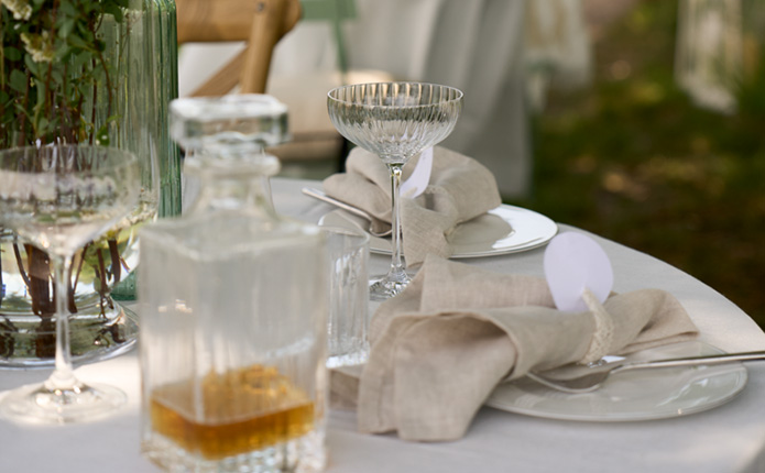 Detailansicht kleiner Tisch mit stilvollen Gläsern, Whiskeyflasche und Servietten mit Namensschildern