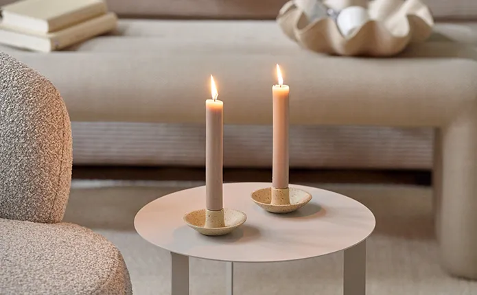 Detailansicht beiger, runder Beistelltisch mit zwei kleinen Kerzenhalter und beigen Stabkerzen
