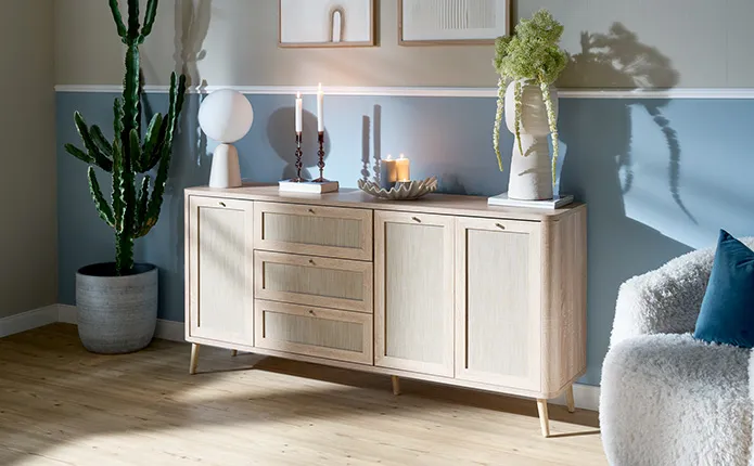 Helle Holzkommode mit Rattan mit Muschelschale, Kugel-Tischleuchte, Vase mit Pflanze und Kaktus daneben