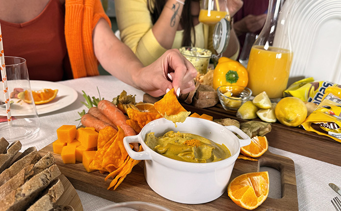 Detailansicht orangene Snacks mit Nachos und Käsedip
