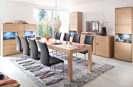 Esszimmer mit Esstisch samt dunkelgrauen Schwingstühlen, Vitrinen und Kommoden im Holzdekor