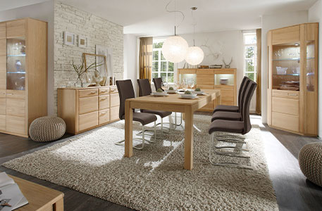 Esszimmer mit Esstisch samt grauen Schwingstühlen, Vitrinen und Kommoden im Holzdekor