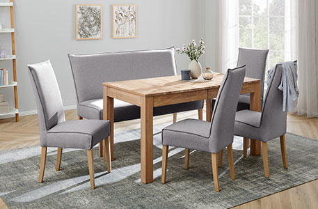 Essgruppe bestehend aus Holz-Esstisch und Polsterstühlen mit grauen Bezügen
