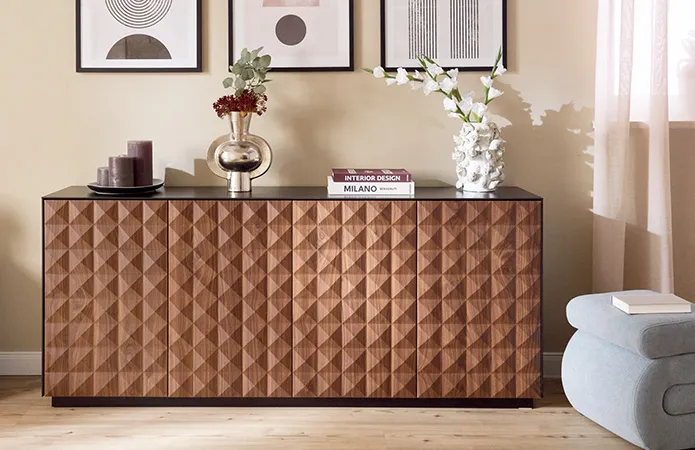 Kommode aus dunklem Holz mit Dekovasen und drei Kunstbildern an Wand