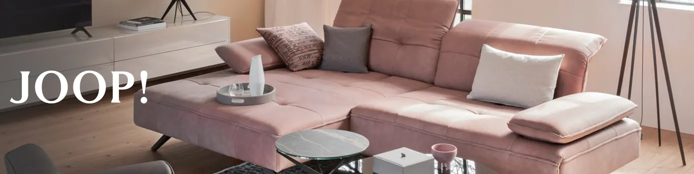 Rosa Ecksofa im Wohnzimmer neben TV Board und Beistelltischen mit dem Hinweis auf die Marke JOOP!