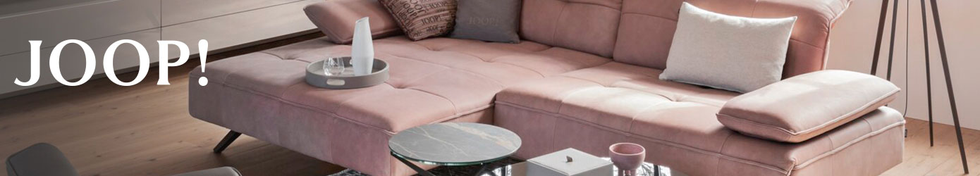 JOOP! - Wohnzimmer mit rosa JOOP Ecksofa, Couchtischen und JOOP-Logo