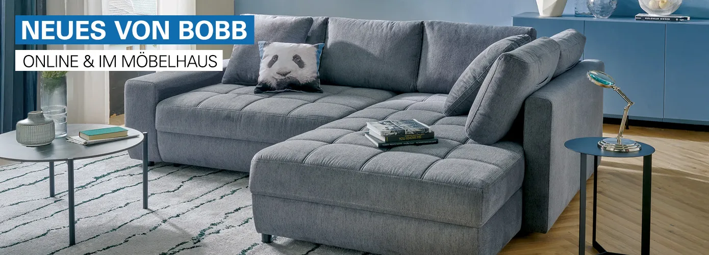 Neues von bobb - online & im Möbelhaus. Graues Ecksofa mit Kissen und Pandakissen in einem Wohnzimmer, Beimöbel, Deko. 