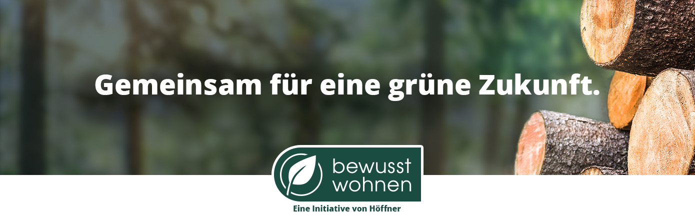 Gemeinsam für eine grüne Zukunft. Holzstämme in Wald. bewusst wohnen. Eine Initiative von Höffner