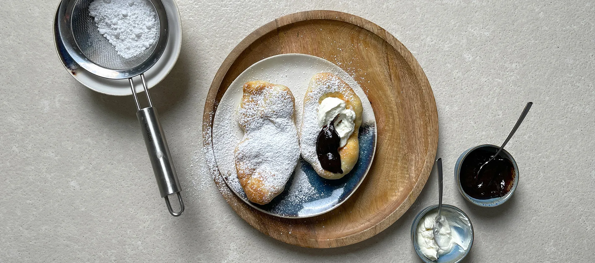 Süße Langos mit Puderzucker, Pflaumenmus und Schmand getoppt