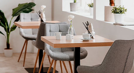 gedeckte Tische aus Holz und graue Polsterstühle in einem Restaurant