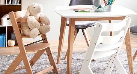 Hochstuhl aus Holz, Hochstuhl in Weiß neben weiß-holzfarbigem Tisch in einem Kinderzimmer, Spielzeug