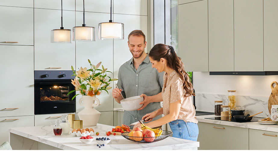 Paar beim Kochen in Küche mit Pendelleuchte über Kochinsel