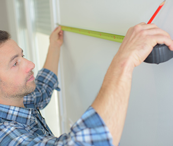 Mann mit einem Maßband, der die Wand vermisst