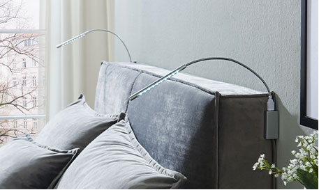 2 flexible LED-Leuchten sind seitlich am Kopfteil eines Boxspringbettes angebracht