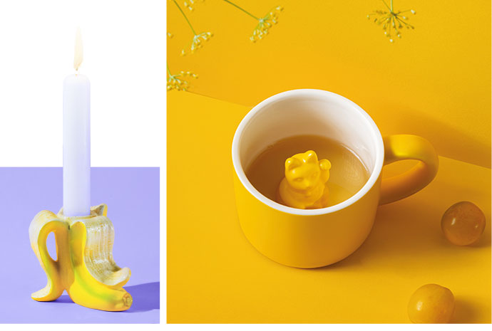 Bild 1: gelber Kerzenständer in Bananenform mit weißer Kerze. Bild 2: weiß-gelbe Tasse mit Tee und gelber Deko-Winkekatze vor gelbem Hintergrund